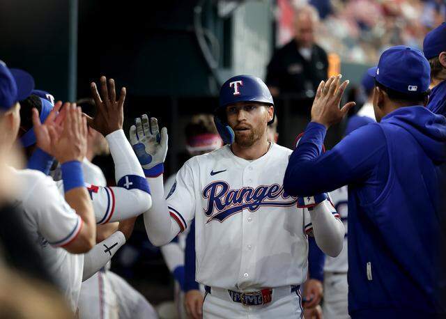 Texas Rangers outfielder Brandon Nimmo high-fives teammates in the dugout after scoring a run to tie the game against the Cincinnati Reds on Friday, April 3, 2026.